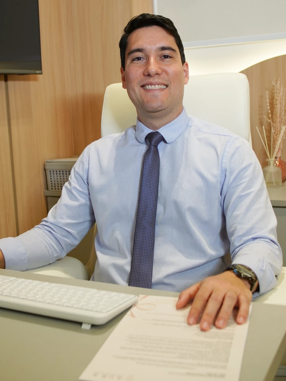Dr. Máspoli Filho sorrindo, sentado em uma poltrona no consultório